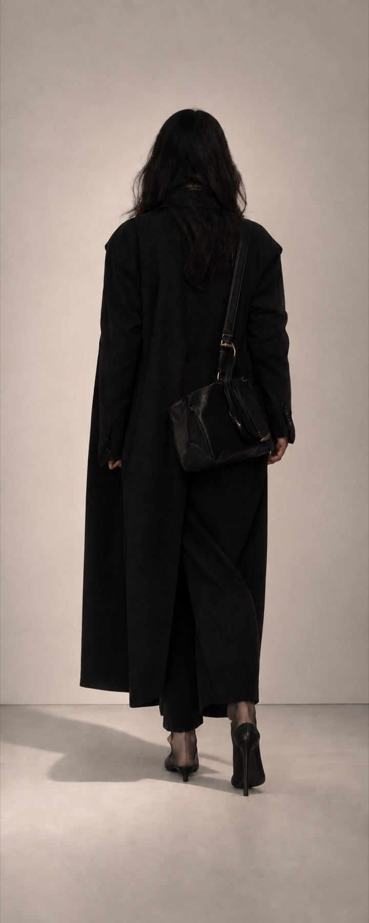 Long black coat and shoulder bag, seen from behind.